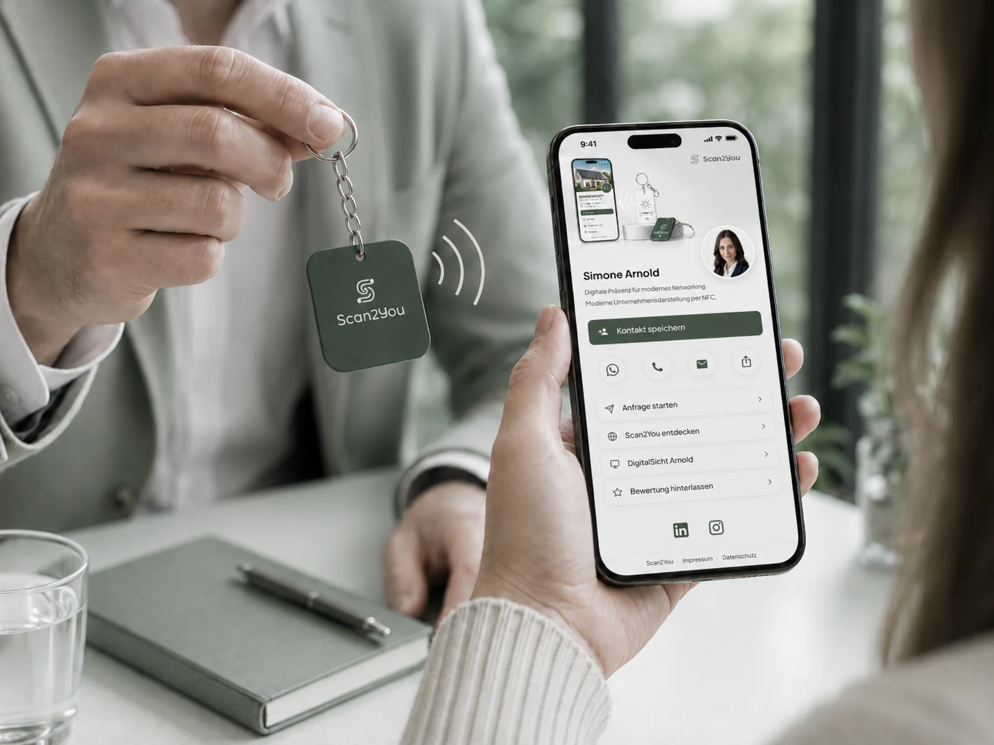 Person zeigt NFC-Anhänger, während eine digitale Business-Präsenz auf dem Smartphone geöffnet ist